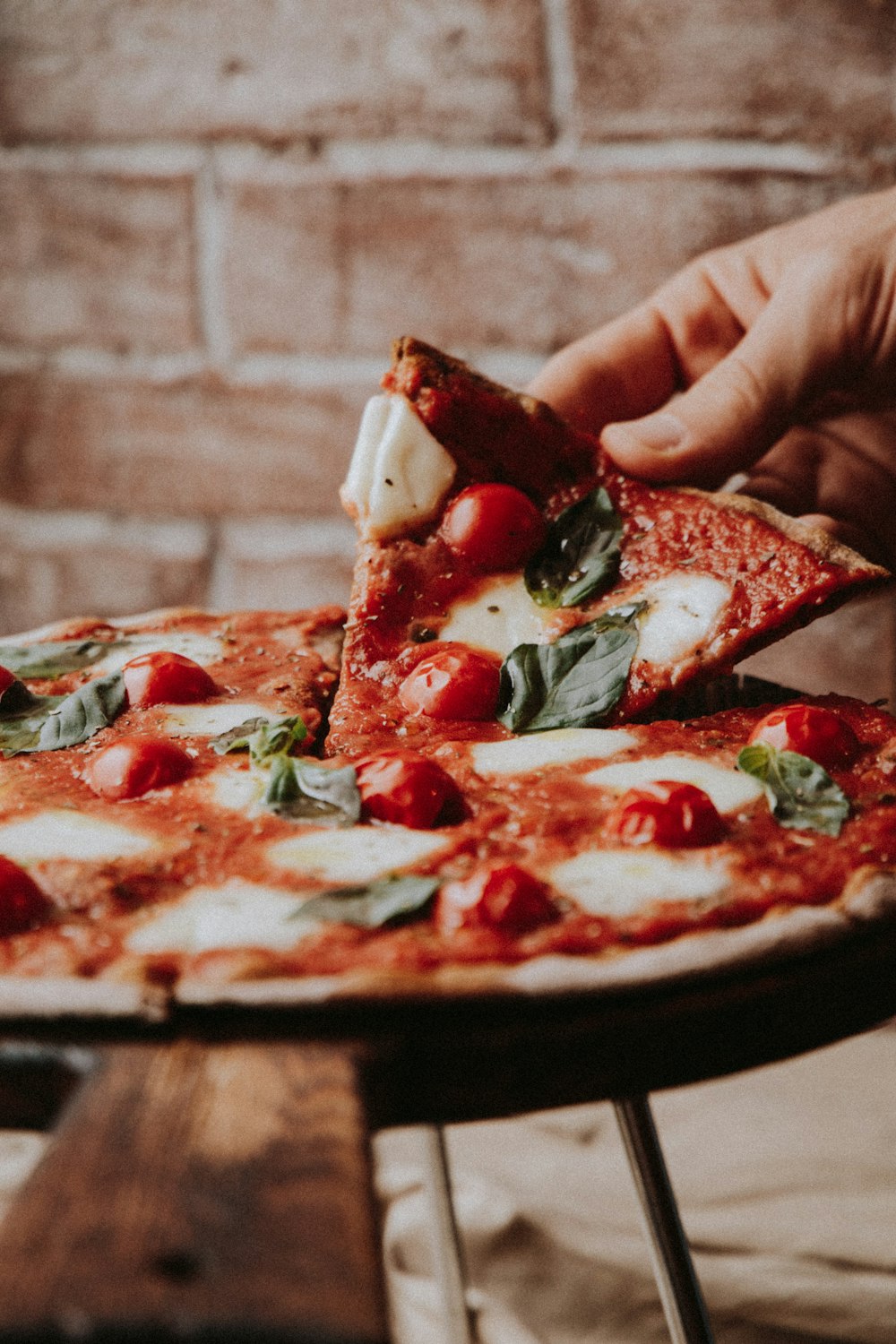 person holding sliced pizza with red sauce