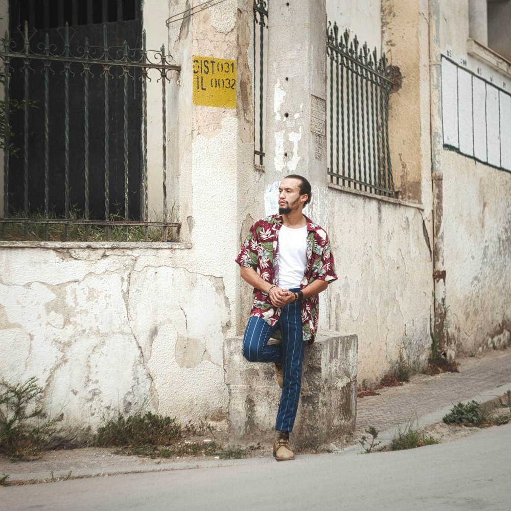 Donna in camicia bianca e jeans blu in piedi accanto al muro di cemento bianco durante il giorno