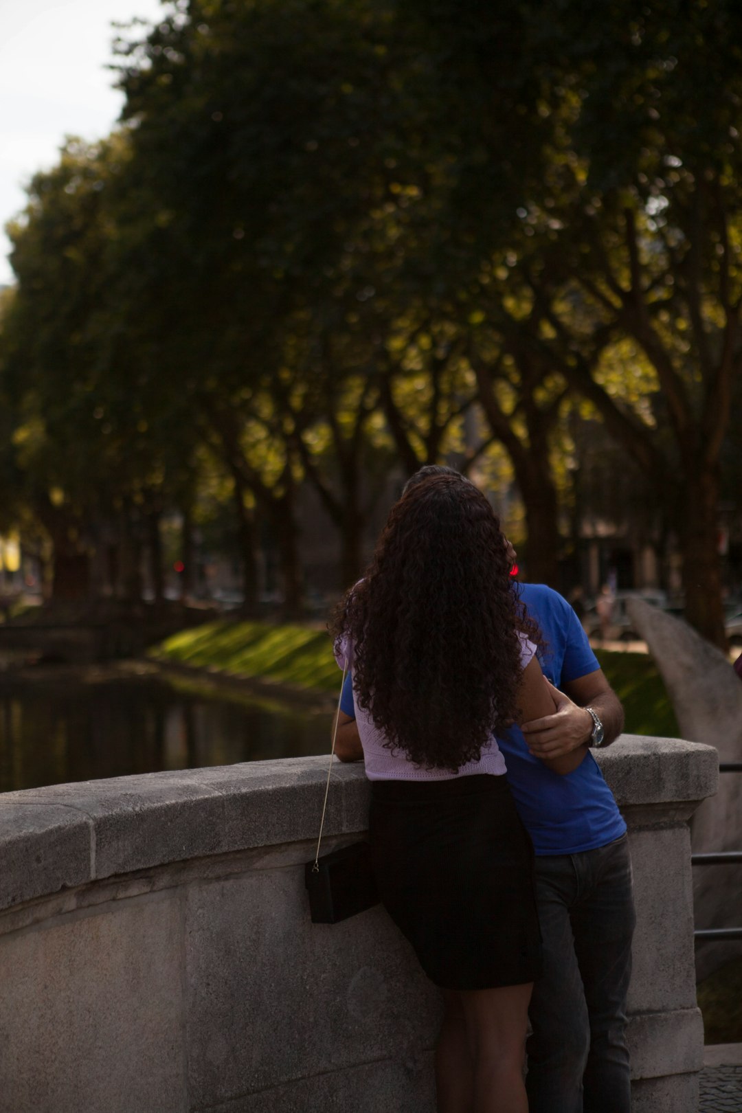 woman in blue long sleeve shirt and black pants standing on concrete bridge during daytime