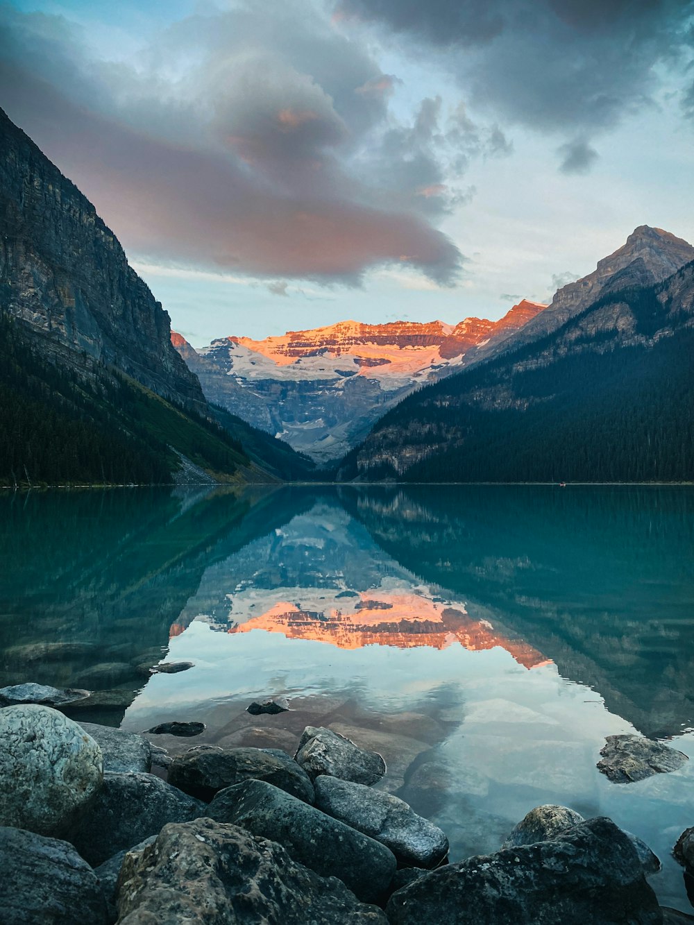 lake near mountain under cloudy sky during daytime