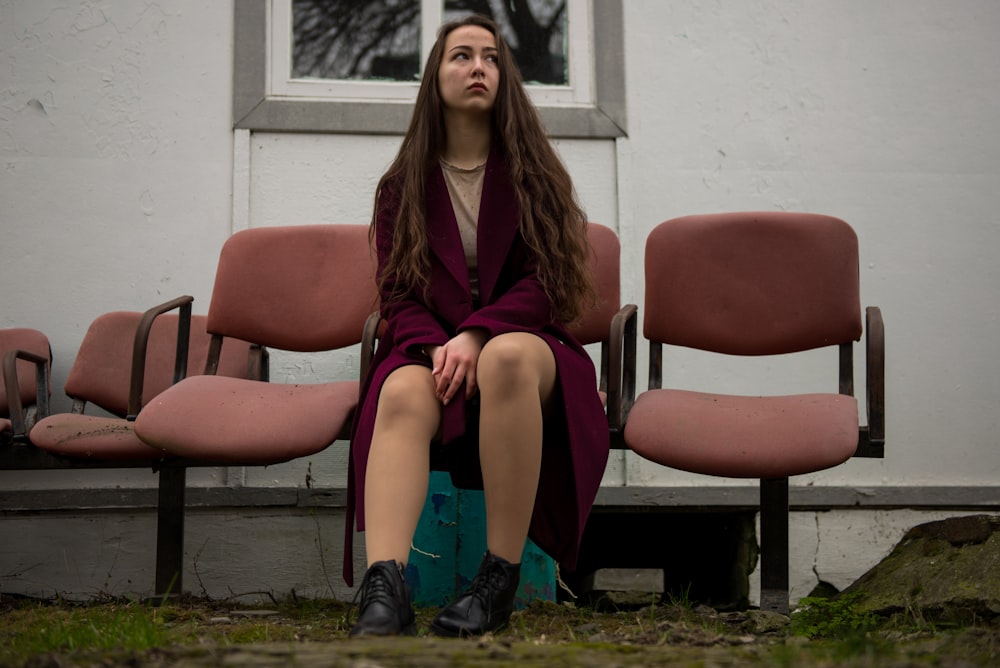 woman in red and brown coat sitting on red chair