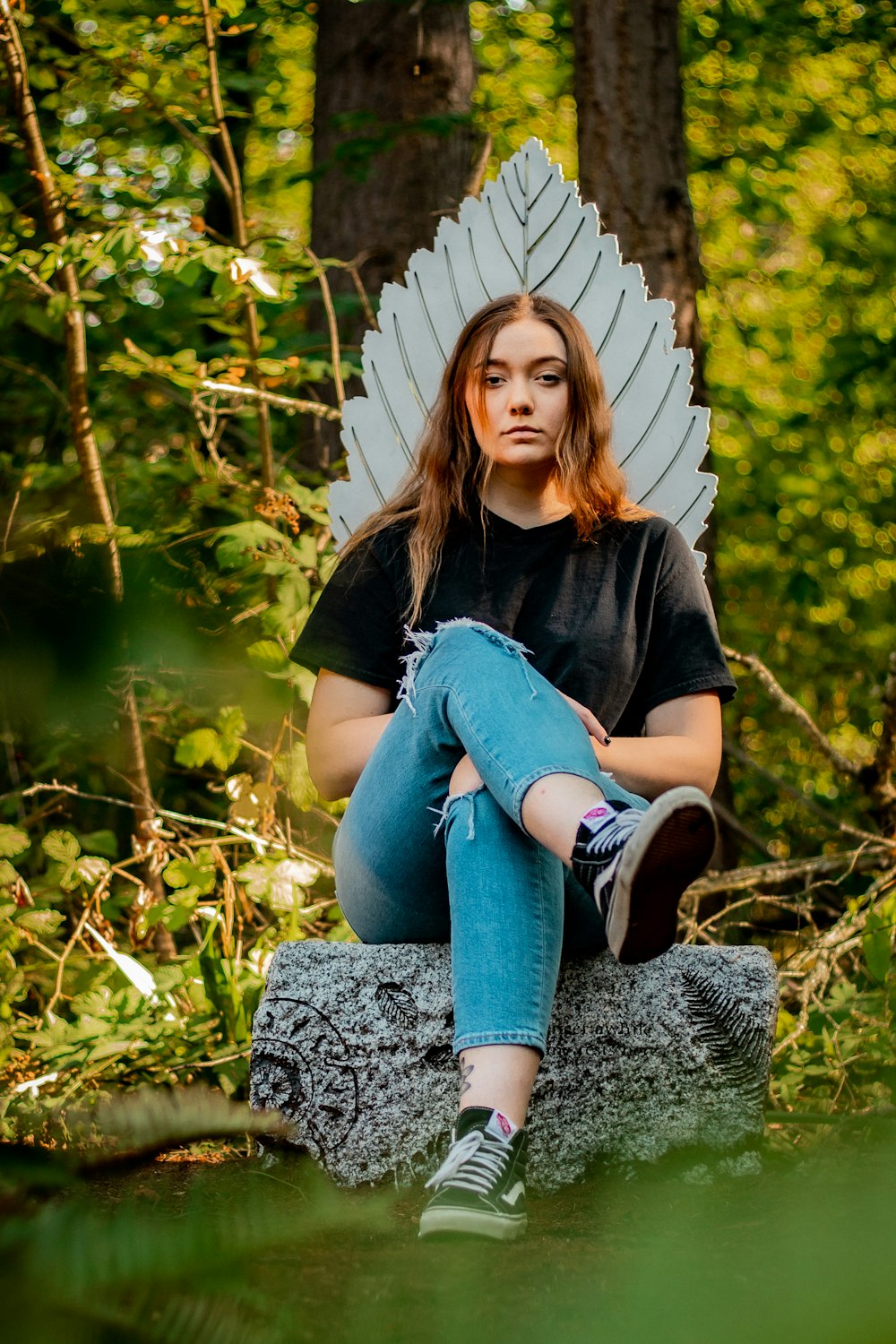woman in black shirt and blue denim jeans sitting on rock