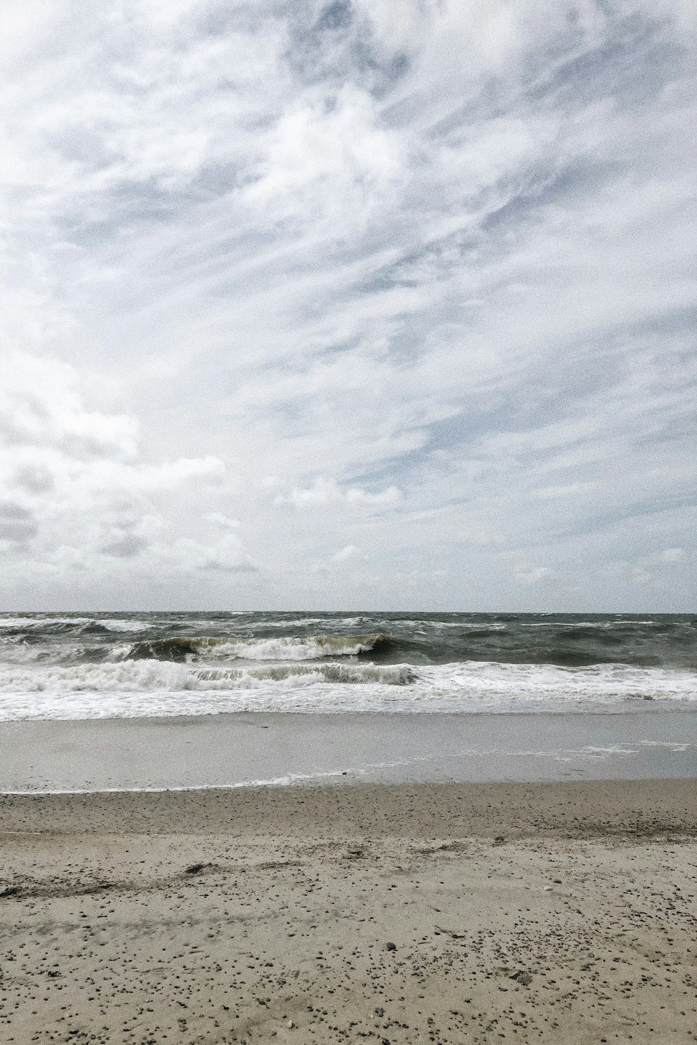 sea waves crashing on shore under white clouds during daytime