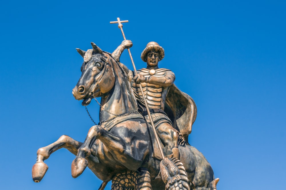 hombre que monta en la estatua del caballo bajo el cielo azul durante el día