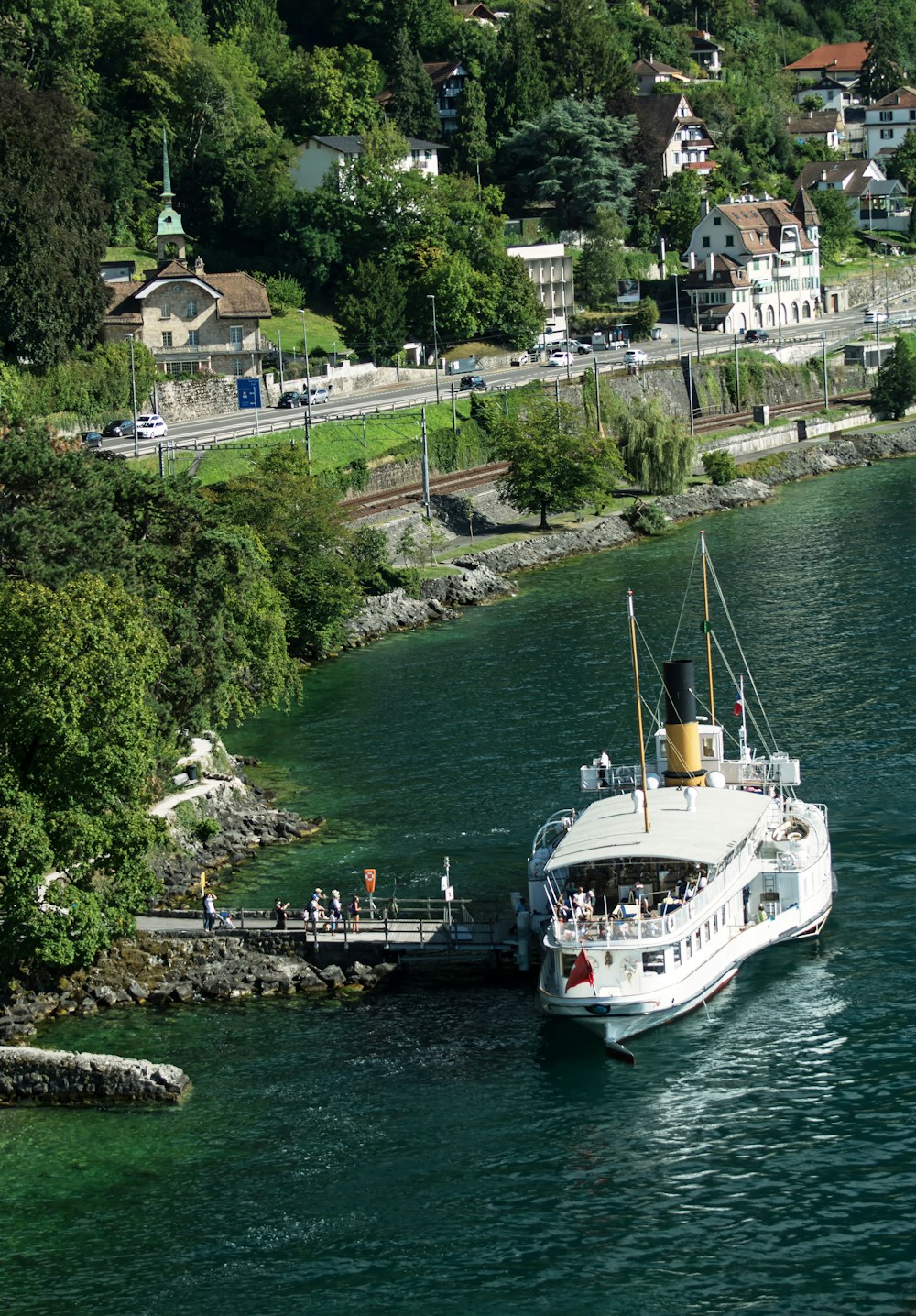 a white boat is in the water near a dock