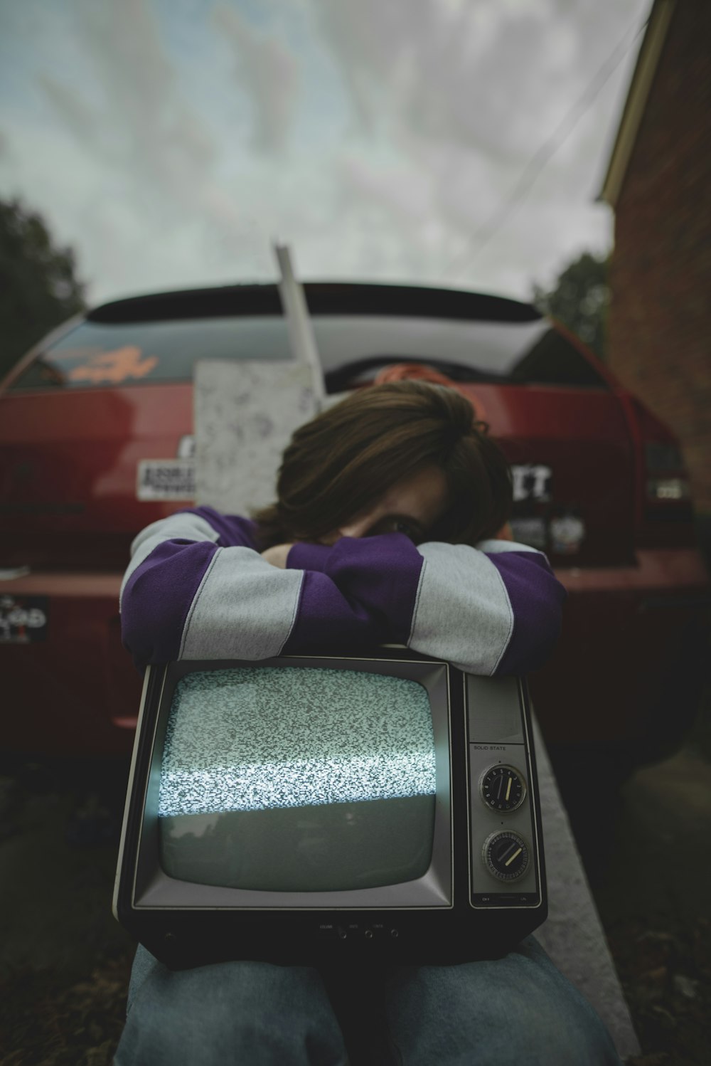 woman in purple and white long sleeve shirt standing beside gray crt tv