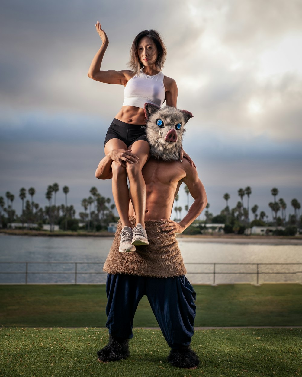 woman in white tank top and blue pants carrying a white and black dog