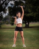A personal trainer guiding a client through strength exercises outdoors.