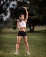 A personal trainer demonstrating proper form during a one-on-one outdoor workout session.