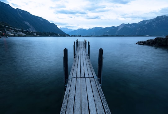 brown wooden dock on lake during daytime in Château de Chillon Switzerland