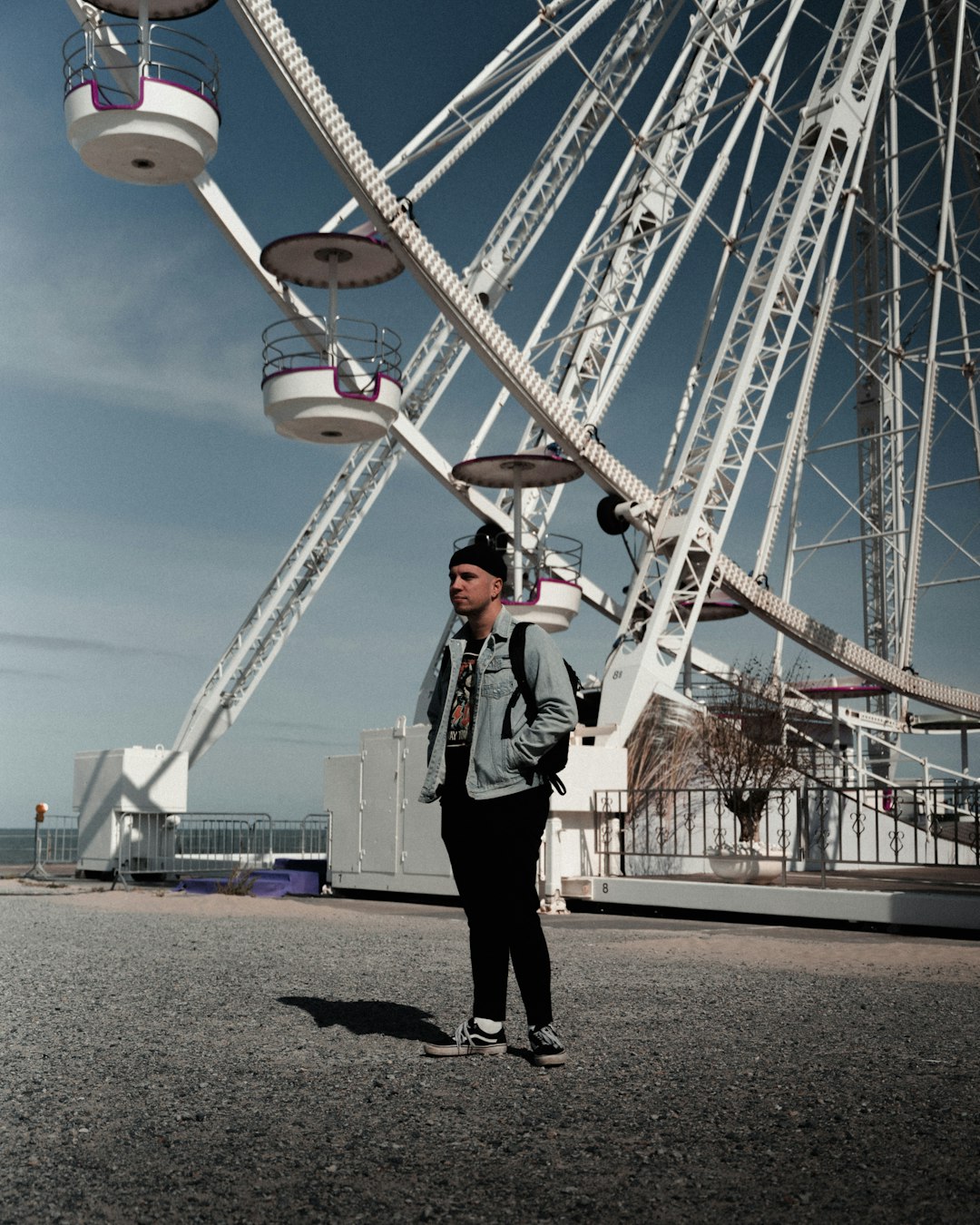 man in black jacket standing beside ferris wheel during daytime