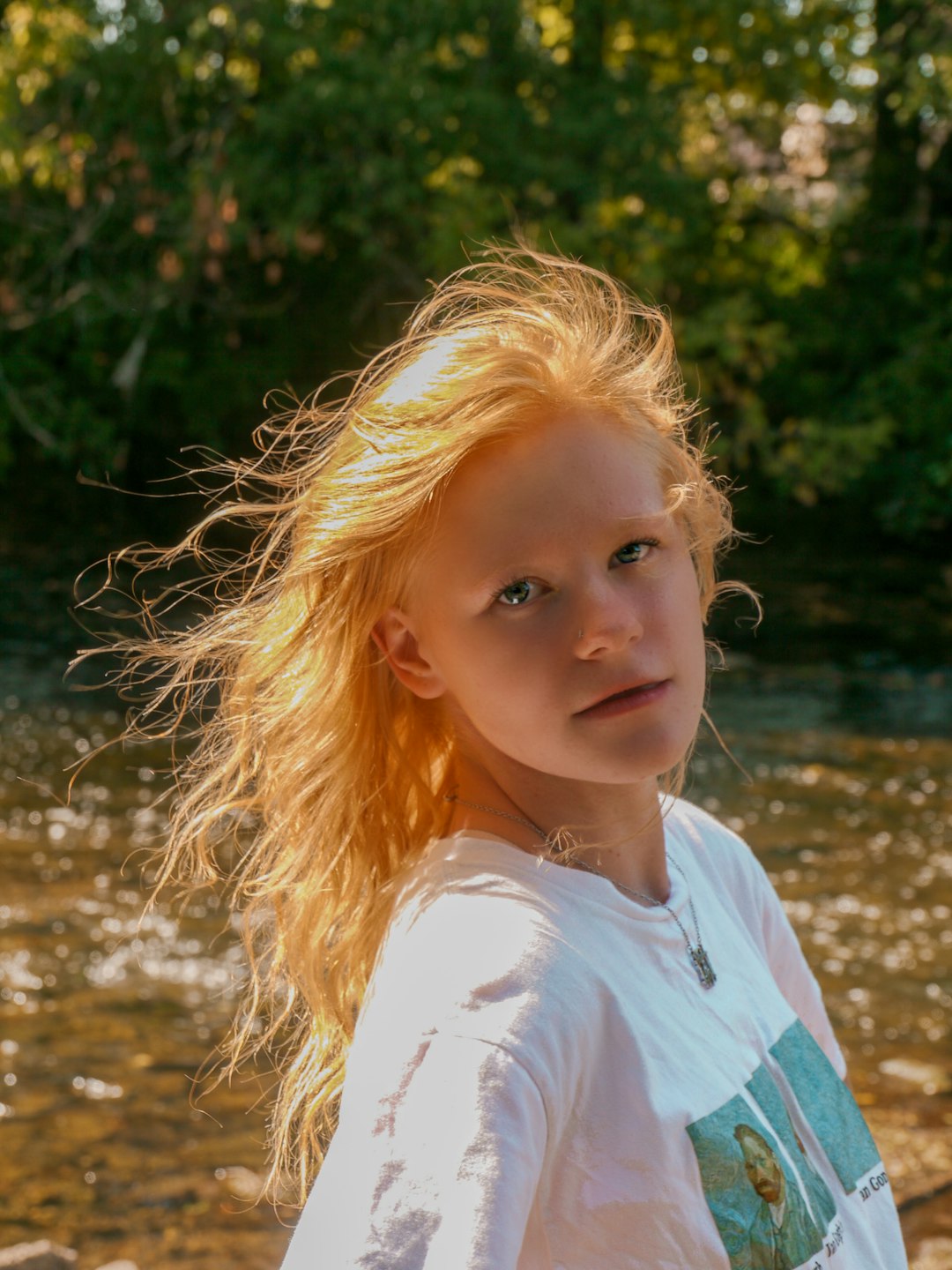 girl in white and blue shirt standing on brown grass field during daytime