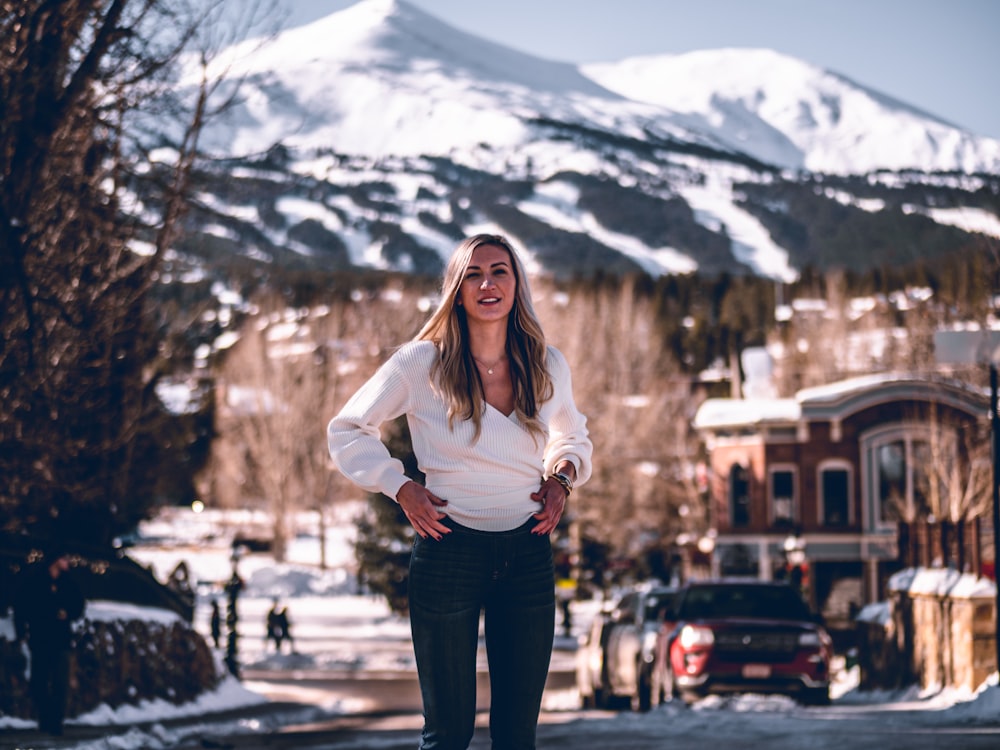 woman in white long sleeve shirt and black pants standing on snow covered ground during daytime
