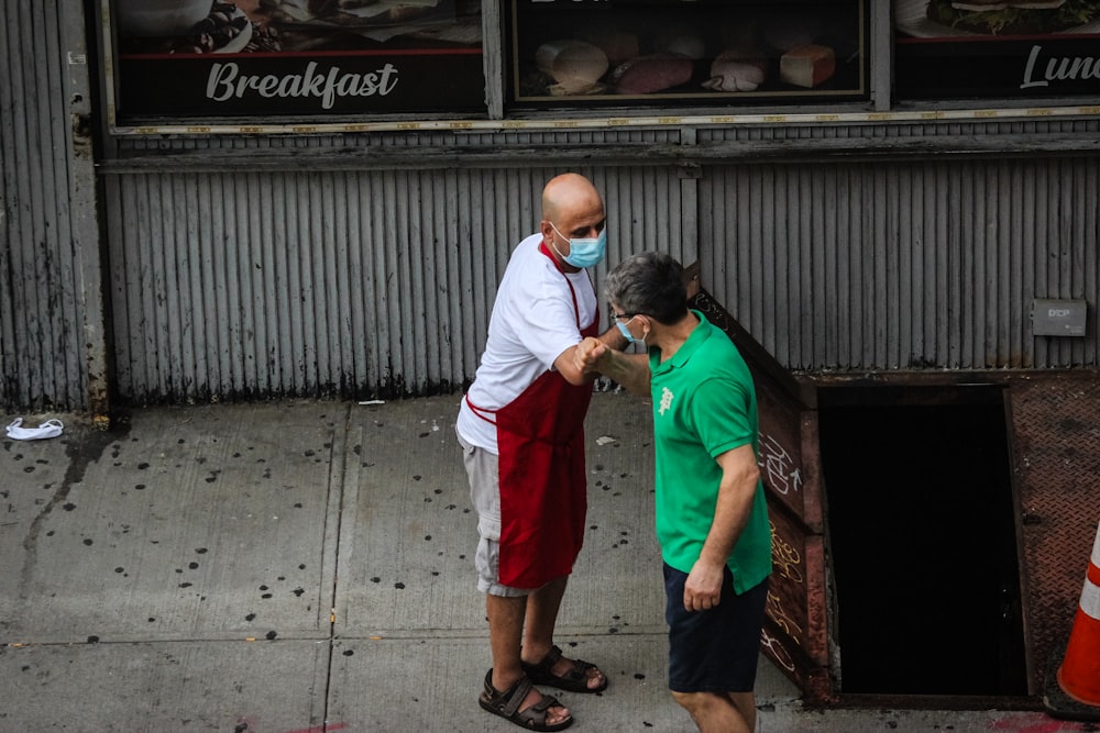 homme en chemise blanche boutonnée et short rouge debout à côté de l’homme en chemise blanche