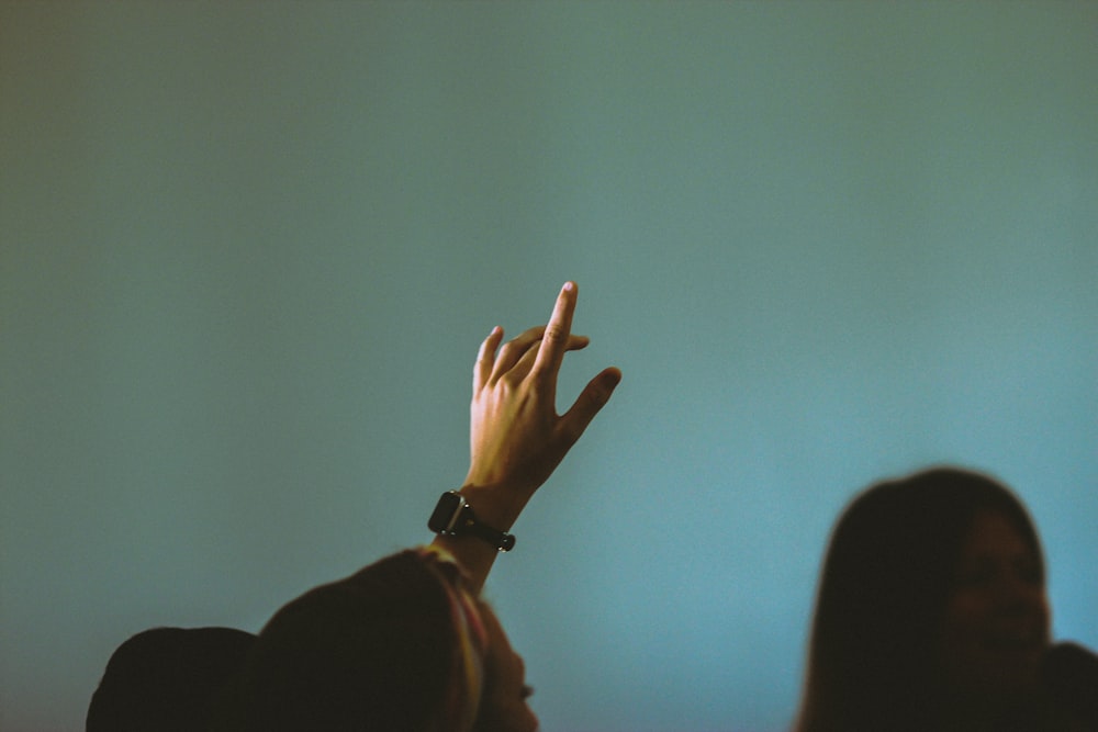 person in black long sleeve shirt raising right hand