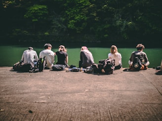 group of people sitting on gray asphalt road during daytime