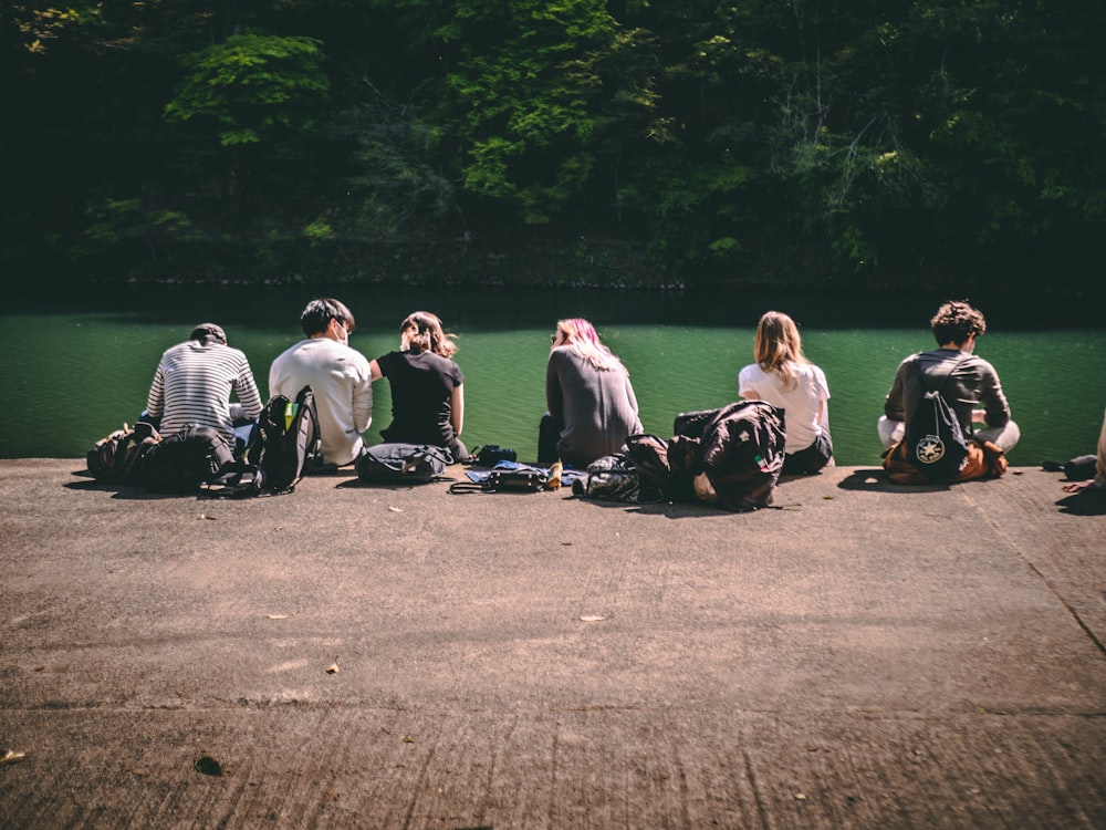 group of people sitting on gray asphalt road during daytime