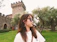Smiling woman standing in front of Bran Castle on a sunny day.