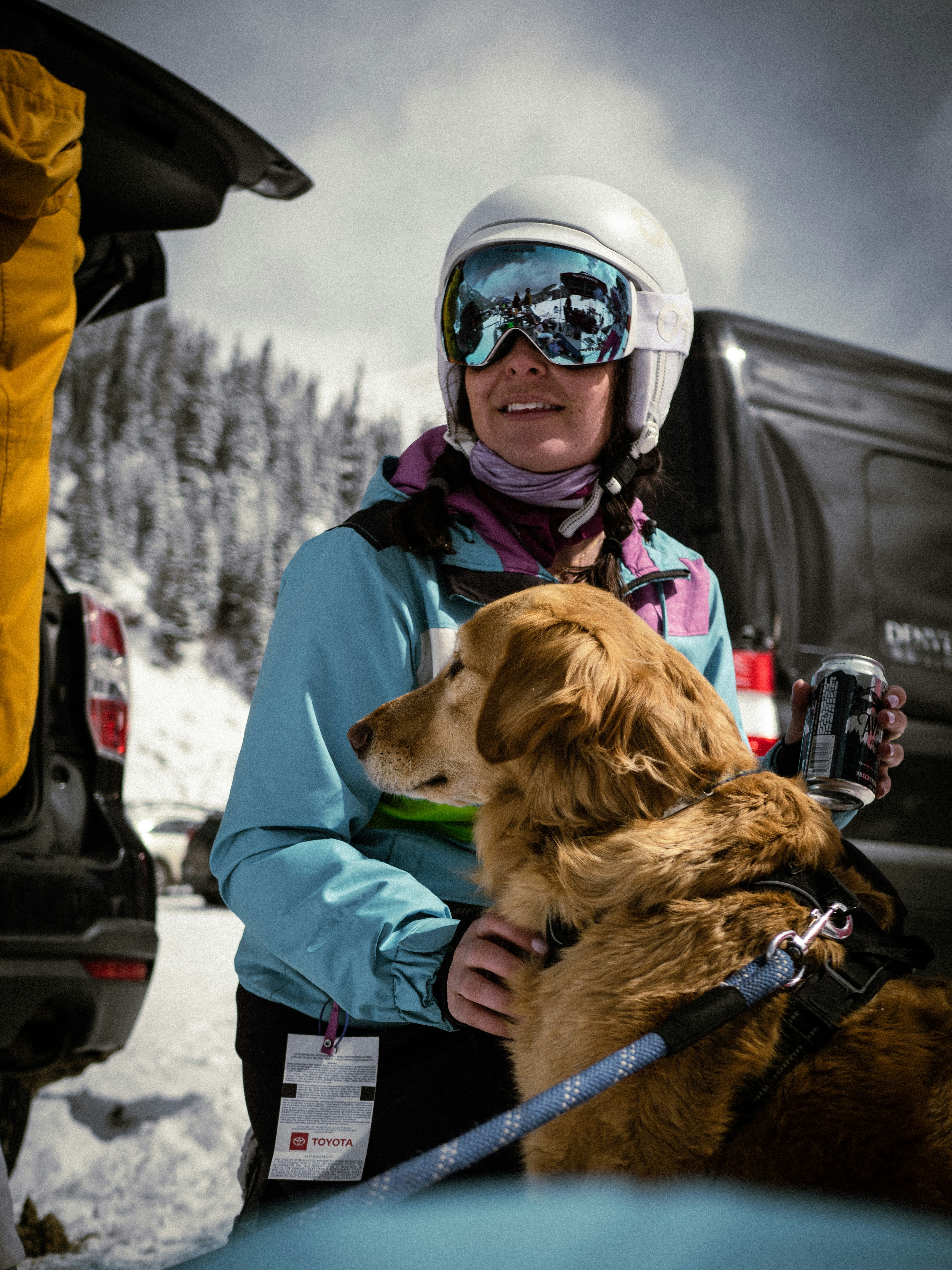 woman in blue jacket and white helmet holding brown dog
