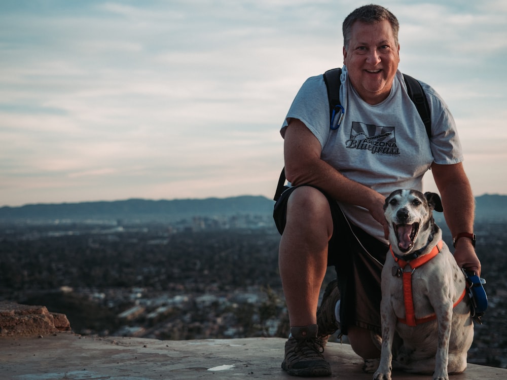 man in blue and black polo shirt holding white short coated dog on beach during daytime