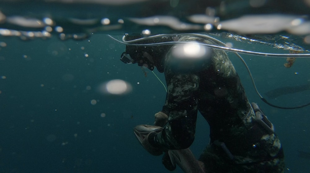 person in black wet suit with black goggles and black helmet