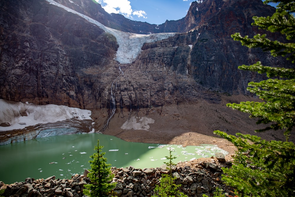 green lake between gray rocky mountains during daytime