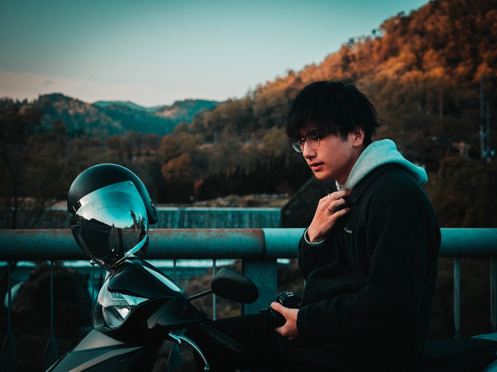 man in black hoodie and black helmet sitting on black motorcycle during daytime