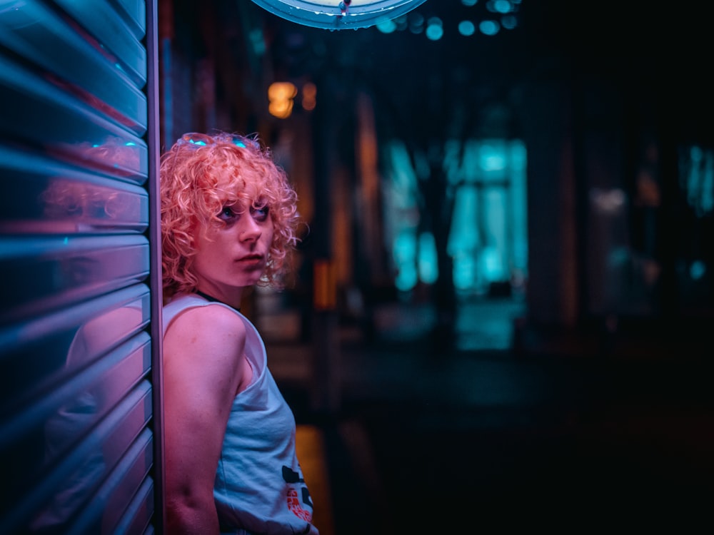 woman in gray tank top standing near pink and white neon light