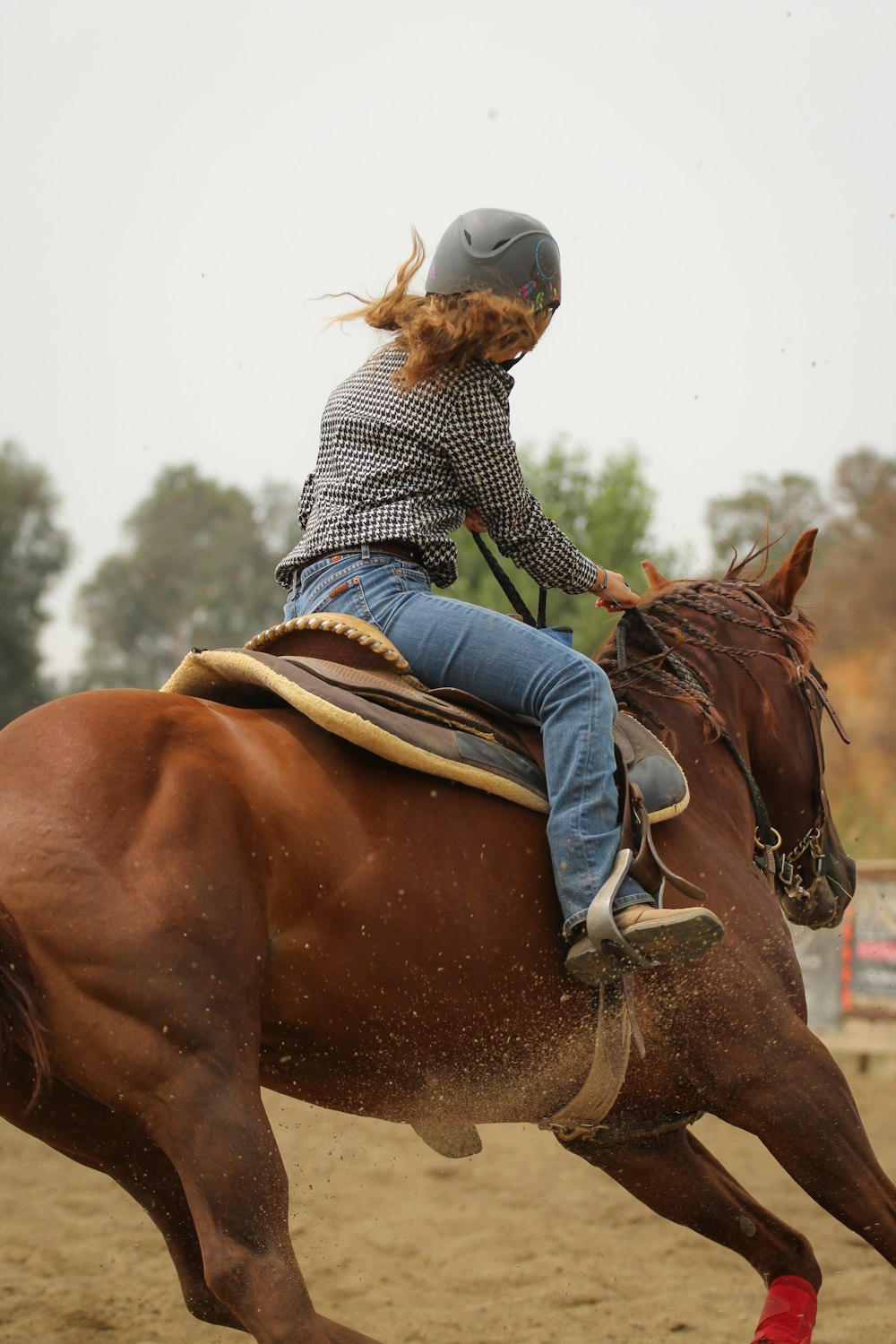 Mujer con camisa de manga larga a rayas azules y blancas montando caballo marrón durante el día
