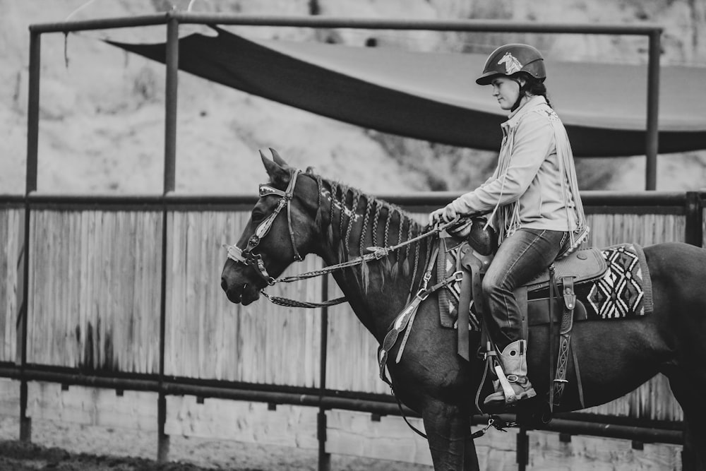 grayscale photo of man riding horse