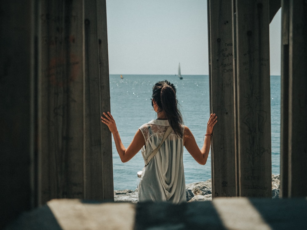 woman in white dress standing on beach during daytime