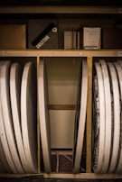 Several folded tables and a bulletin board are stored vertically against a wall. There are also various boxes and a framed paper label titled 'Blue Ribbon Offering' on the shelf above.