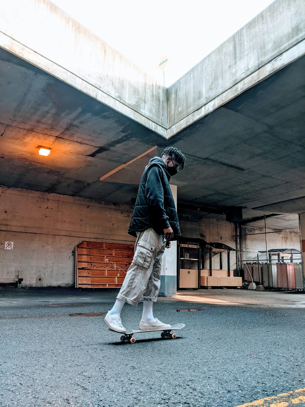 man in black jacket and white pants walking on gray asphalt road during daytime