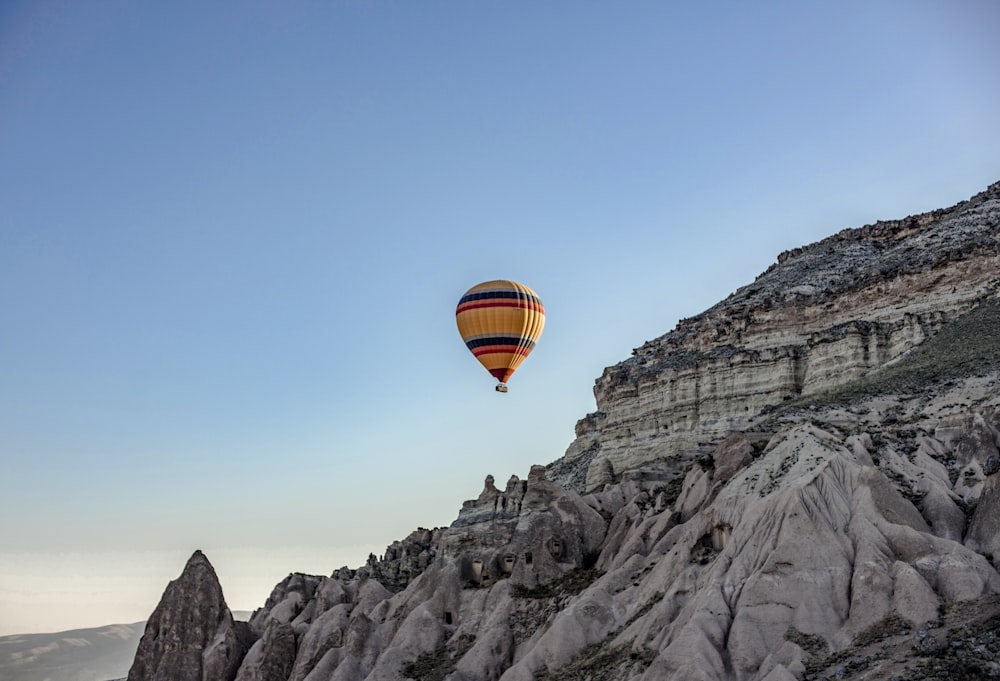 hot air balloon flying over rocky mountain during daytime