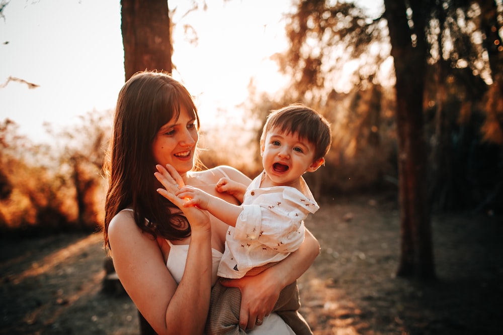 woman in gray tank top carrying baby in white shirt