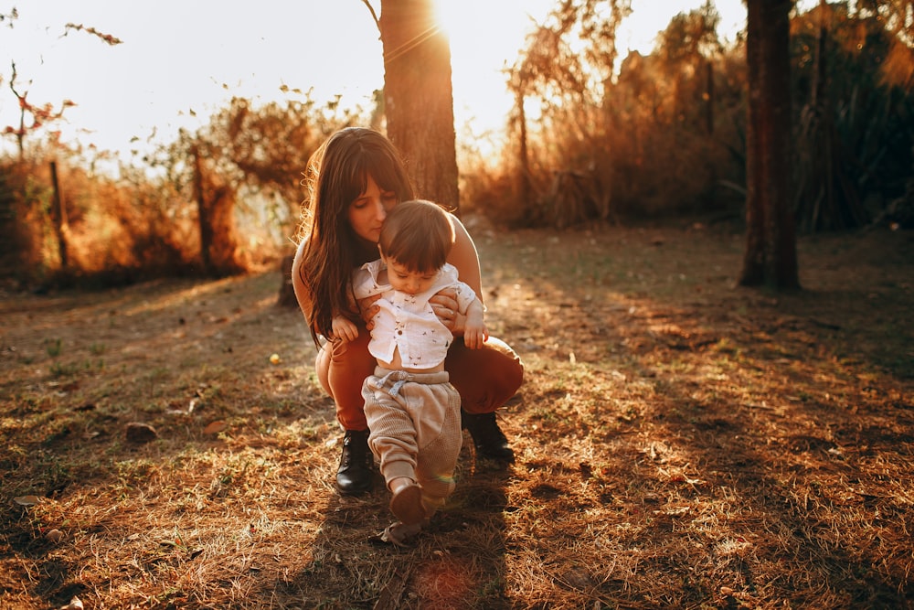 girl in white shirt and brown pants sitting on ground