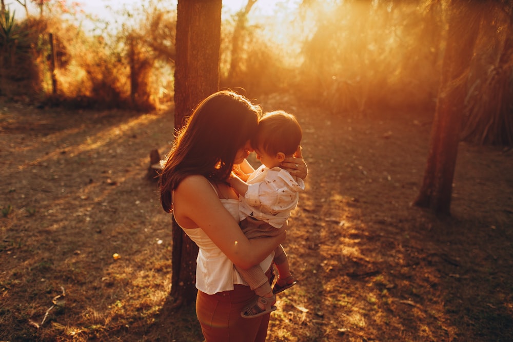 woman in white shirt carrying girl in white shirt