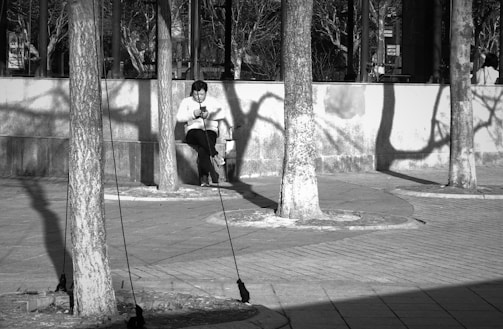 An outdoor scene of a person using their phone on a park bench, with money symbols floating around.