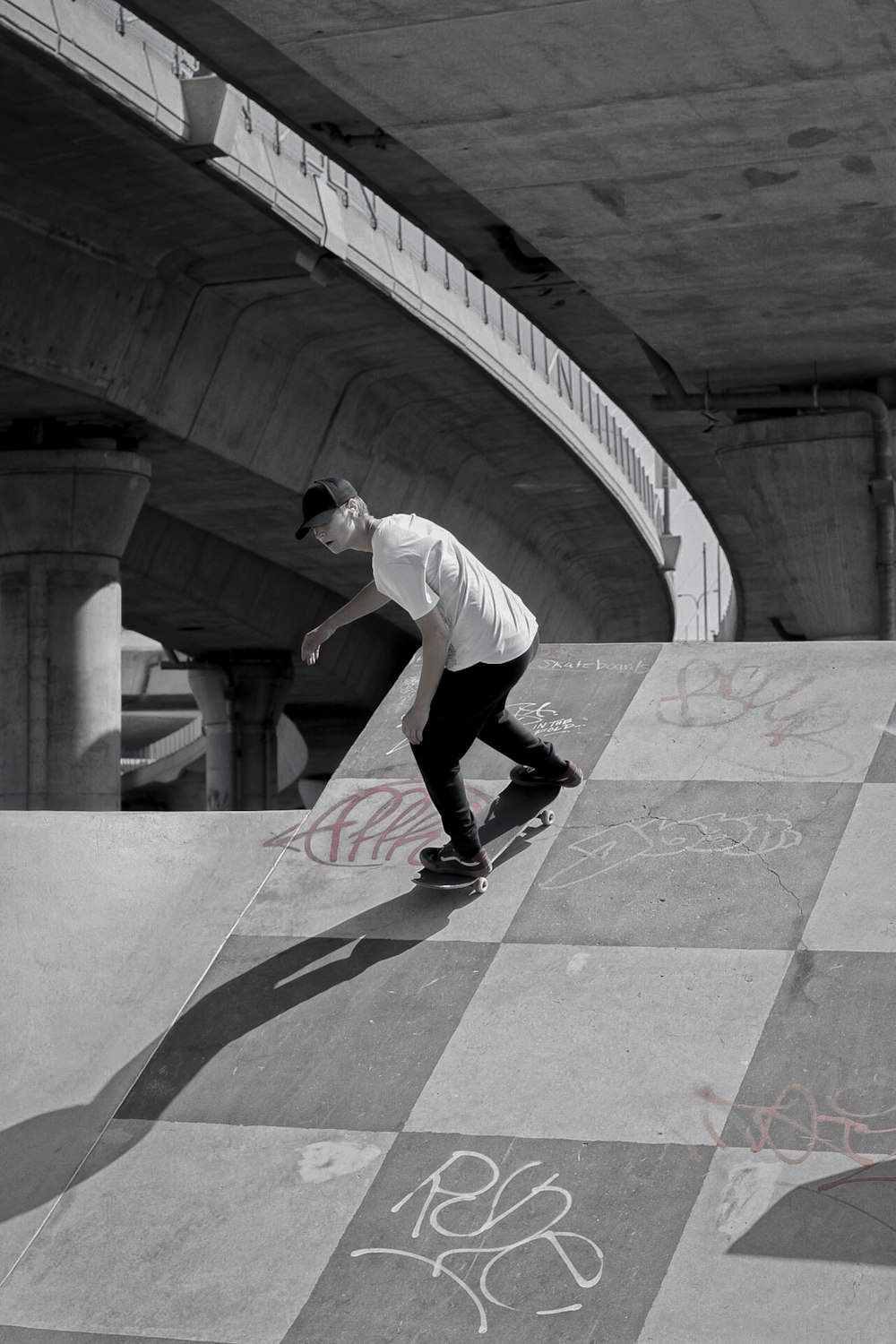 Hombre con camiseta blanca y pantalones cortos negros caminando sobre pavimento de concreto gris