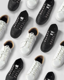 Sleek black and white sneakers arranged beside elegant leather handbags on a minimalist white background.