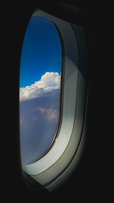 A window seat view showing clouds and blue sky during an international flight.