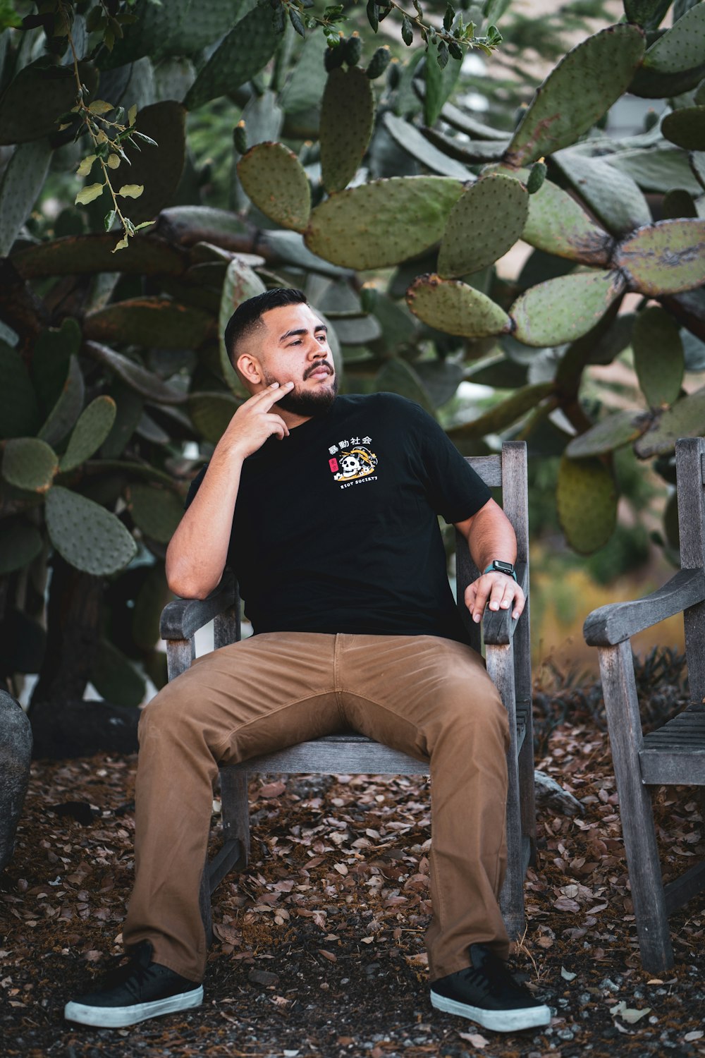 man in black crew neck t-shirt sitting on brown wooden armchair