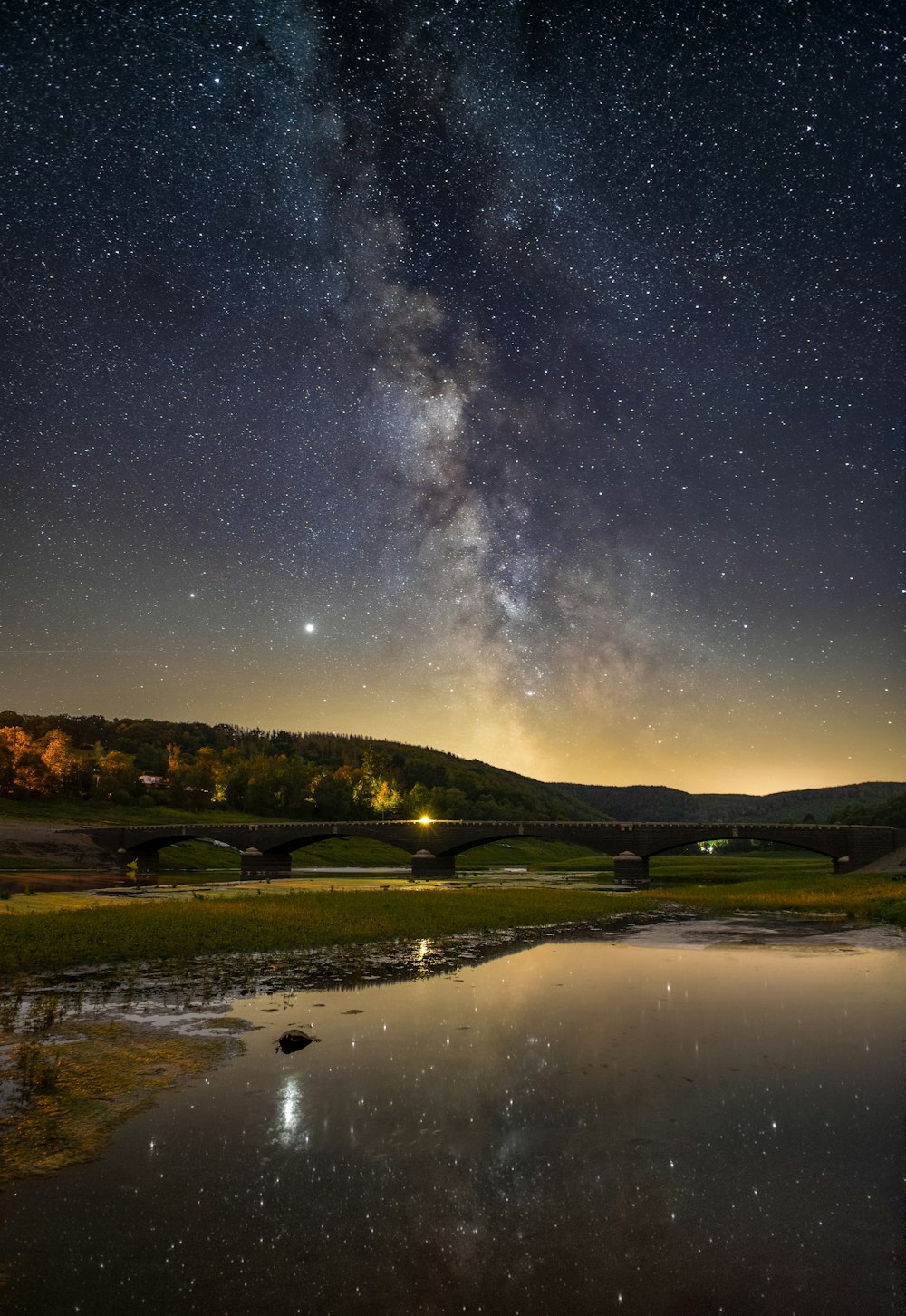 green grass field near lake under blue sky during night time