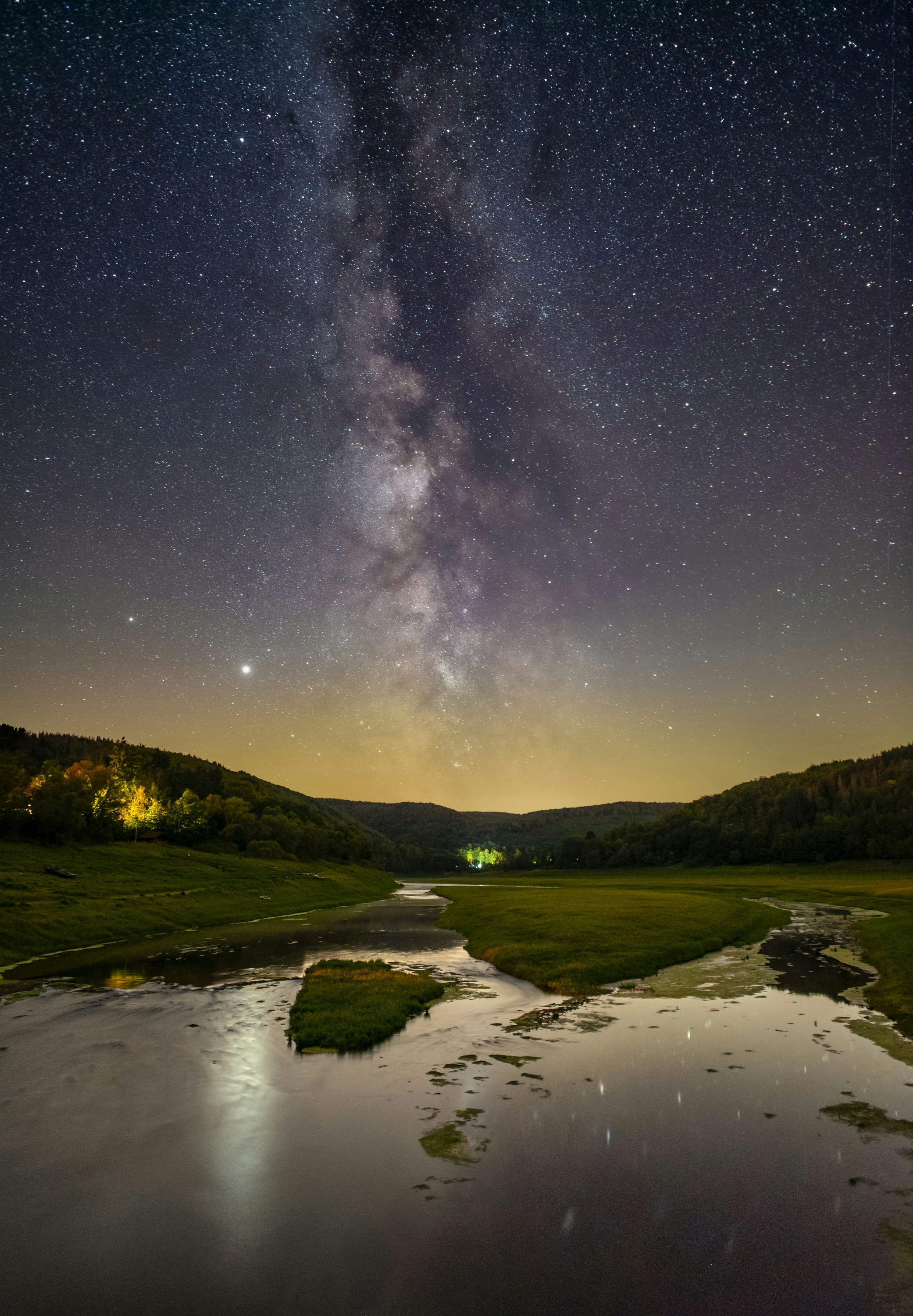 lake in the middle of green grass field under starry night