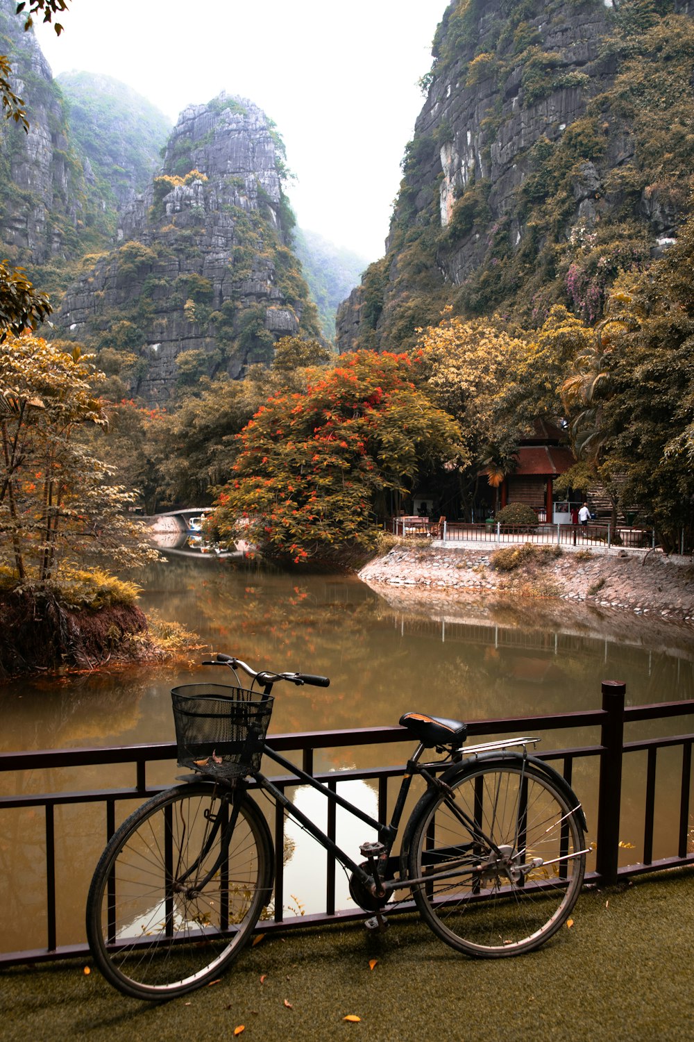 black bicycle beside brown wooden fence near river during daytime