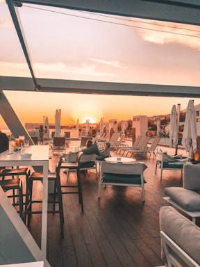 Elegant outdoor lounge area with high-end furniture under a large umbrella during sunset.