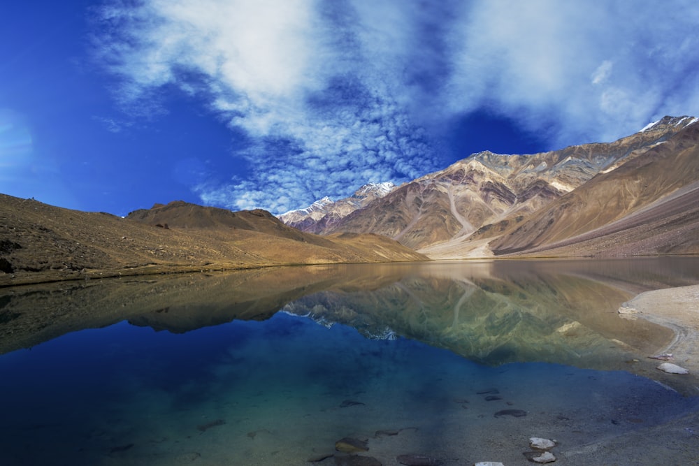 Brauner Berg in der Nähe von Gewässern unter blauem Himmel tagsüber