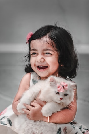 a little girl holding a white cat in her arms