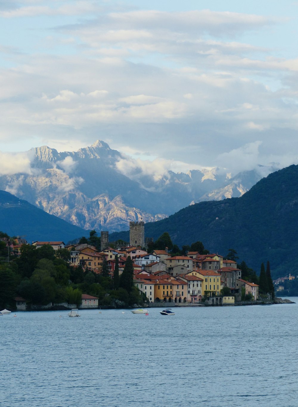 brown and white concrete building near body of water under white clouds and blue sky during