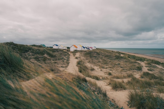 white and red tent on green grass field under cloudy sky during daytime in Gouville-sur-Mer France